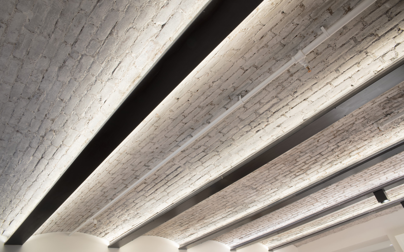 A repeating brick barrel-vaulted ceiling is painted white and is illuminated with recessed lighting in this Tribeca loft