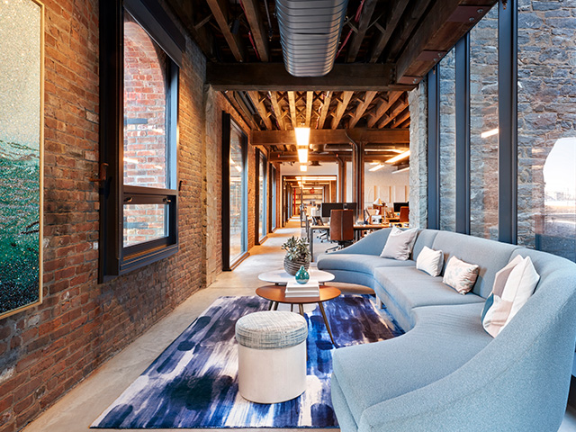 A long corridor with arched windows facing the Manhattan Bridge is used for multiple seating areas perfect for casual meetings at West Elm Headquarters.