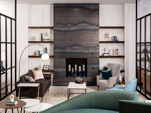 A furniture grouping is anchored by a soaring, gray-tined stone fireplace surround at the Workspace Minneapolis showroom of West Elm