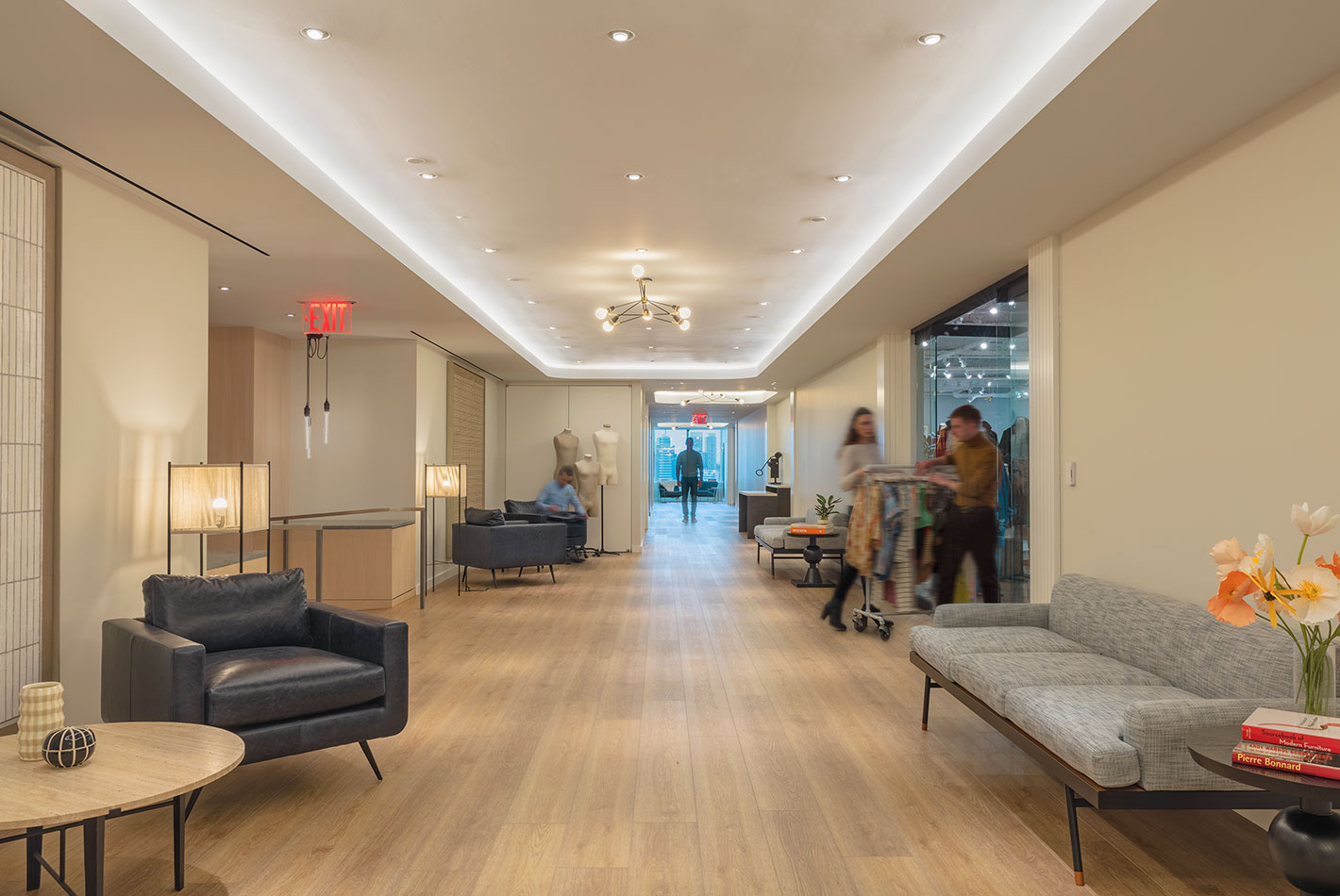 Cove lighting illuminates the reception area at J Crew Headquarters. Several seating areas are arranged on the bleached oak floors.