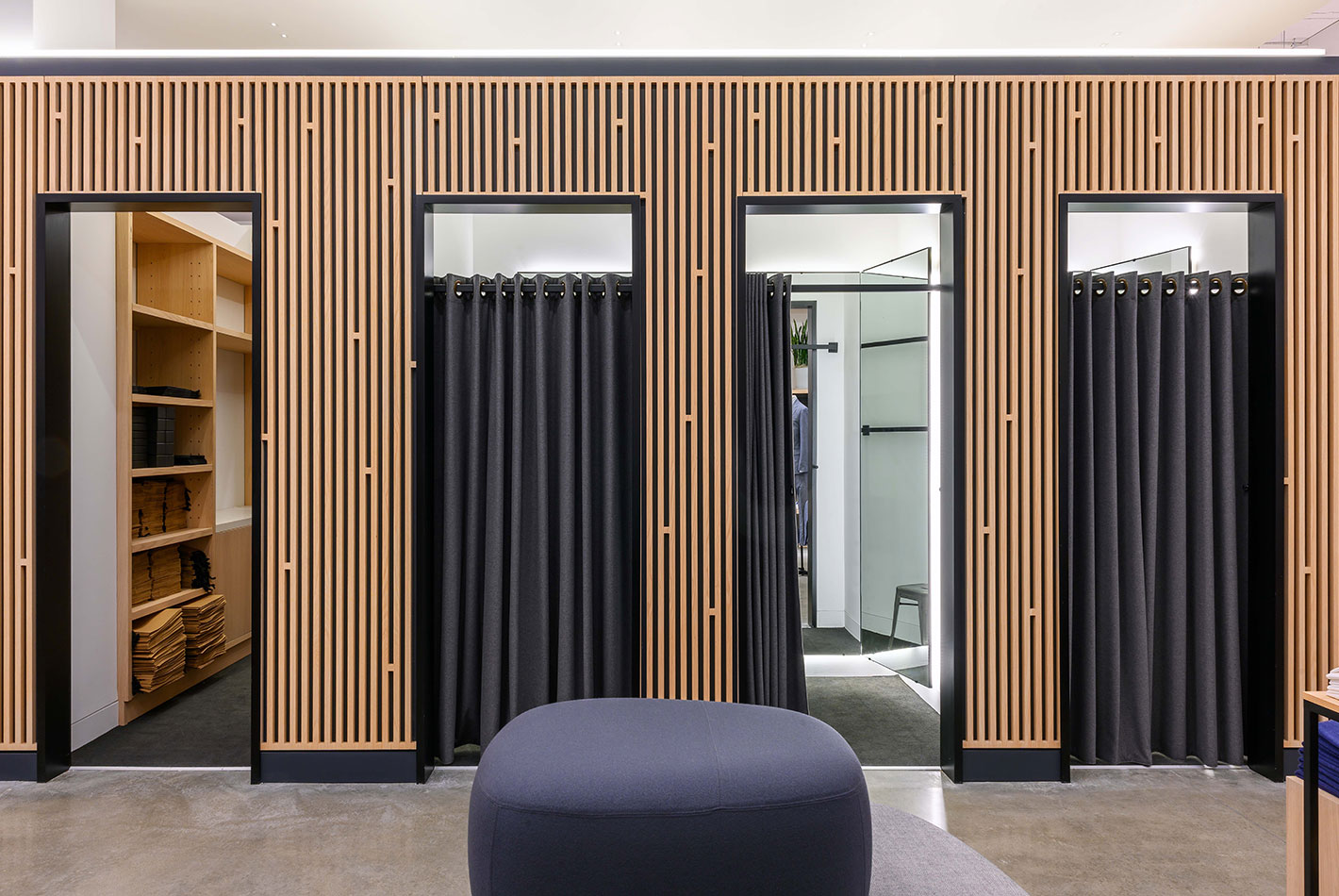Gray flannel curtain panels cover the dressing rooms at J Crew's newly designed store. Slatted-wood walls separate the spaces.