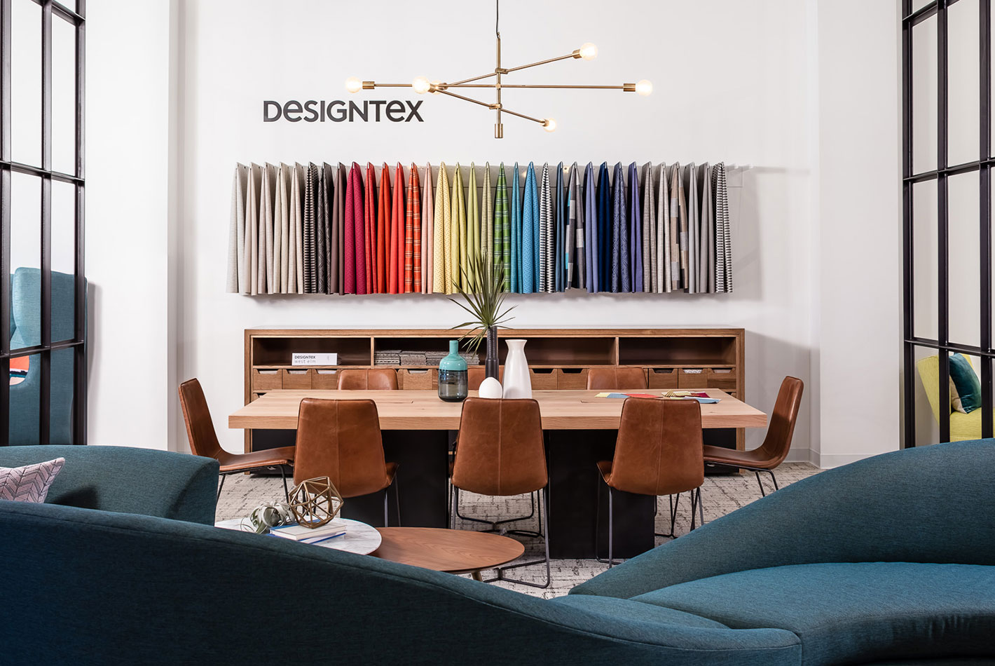 A collection of DesignTex fabrics hangs on a wall above a conference room table in West Elm's Workspace showroom in Minneapolis.
