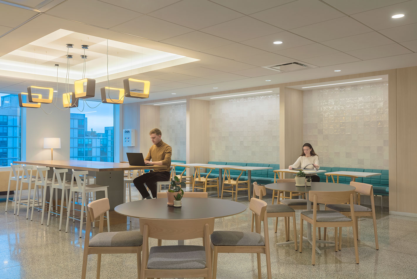 The employee cafeteria at J Crew Headquarters has multiple seating areas, including a long upholstered banquette on one wall.