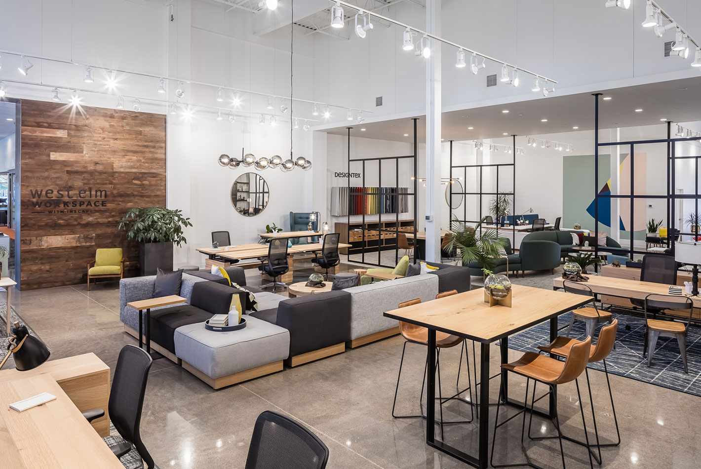 A wide angle shot of the entire West Elm Workspace showroom in Minneapolis. Multiple seating area, work areas, and casual spaces are arranged on a polished stone showroom floor