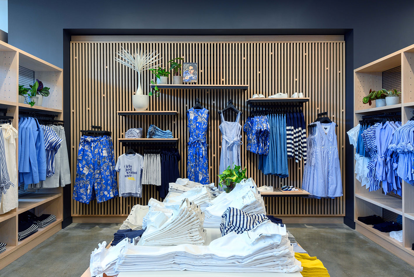 The women's clothing area at J Crew has oak shelving, blue-gray walls, and polished floors.