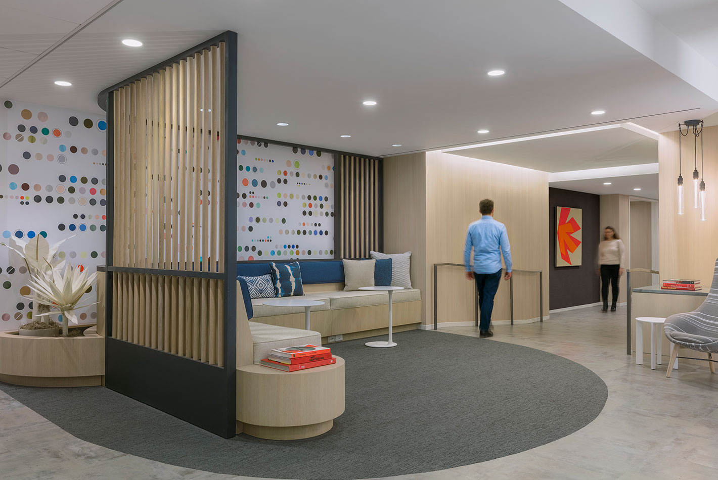 The reception area at J Crew's headquarters features bleached wood floors, white marble, and textural wall covering. A casual sofa area is also featured.