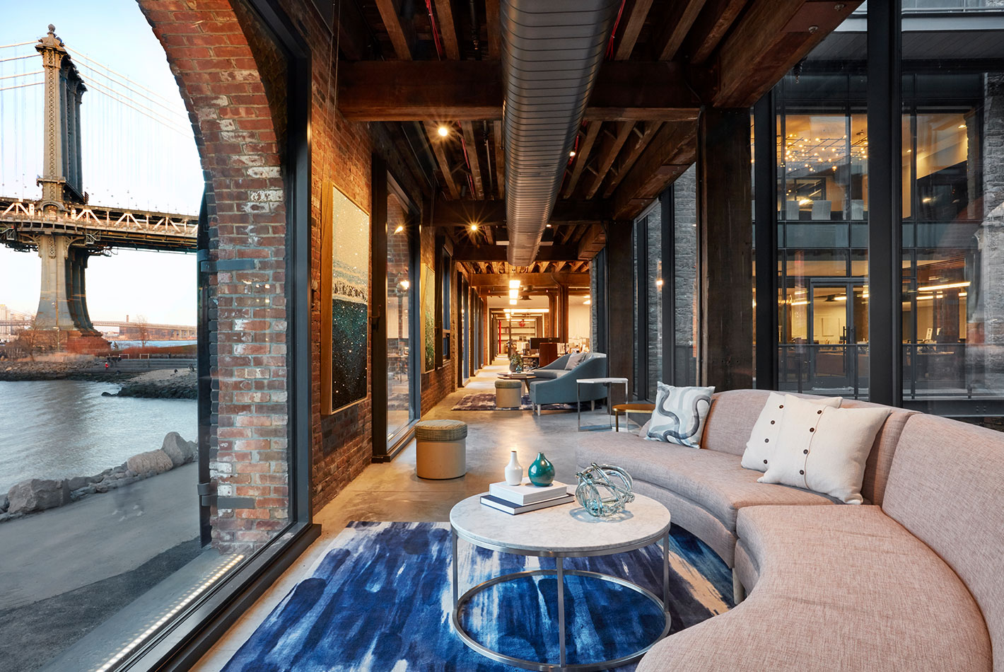 A long corridor with arched windows facing the Manhattan Bridge is used for multiple seating areas perfect for casual meetings at West Elm Headquarters.