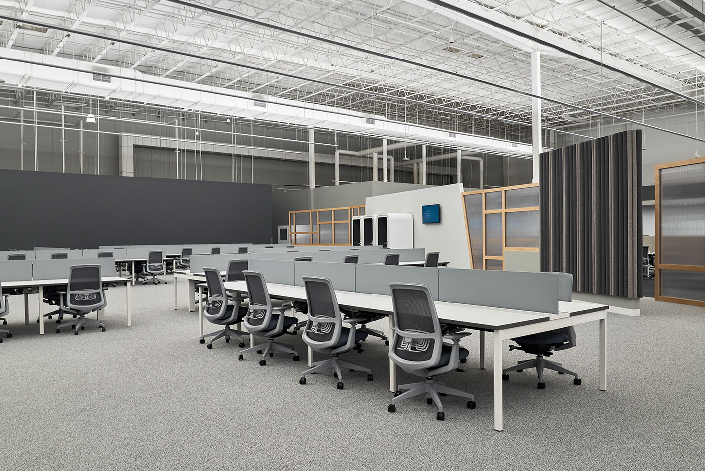 Multiple long, double sided desks for workers at Postmates Headquarters. The furnishings are in a color palette of white and soft grays