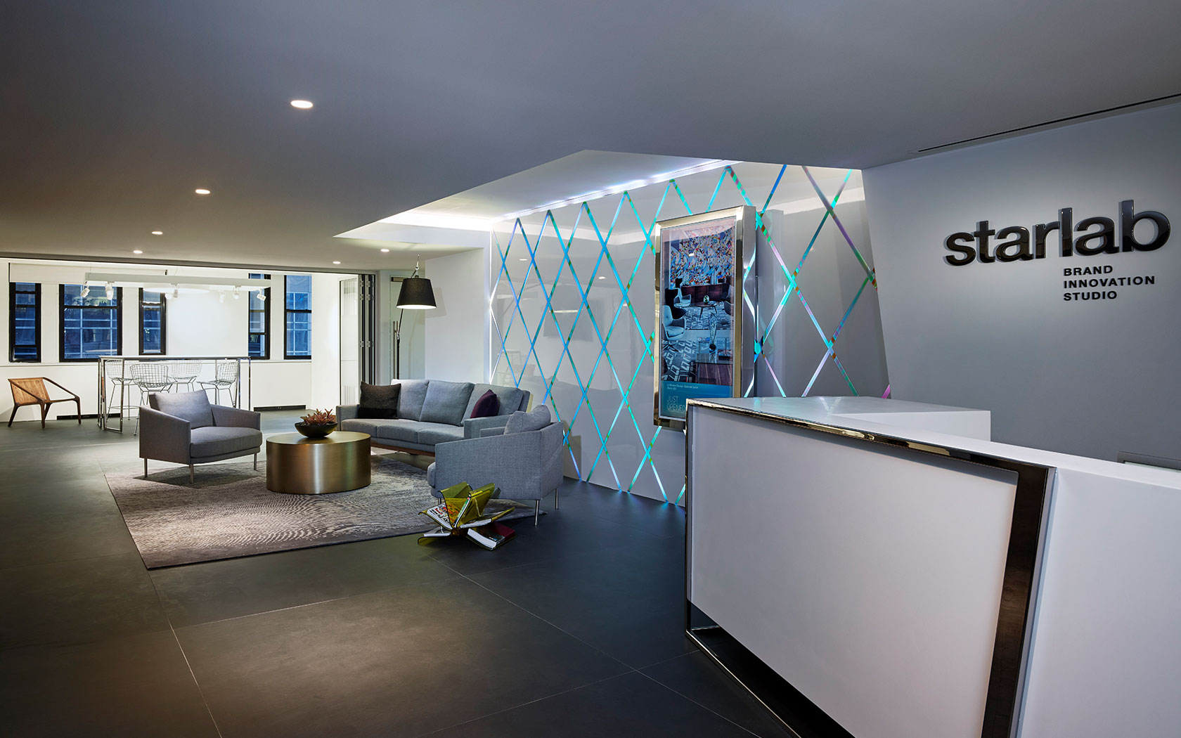 The lobby of Starwood Design Studio features upholstered seating and a brightly lite diamond-patterned wall