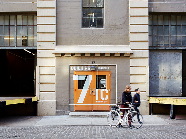 The industrial entry to the West Elm Maker's Studio with orange painted doors.