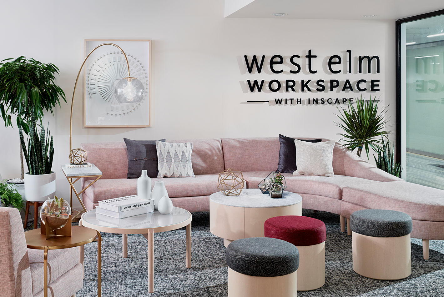 A pink serpentine sofa and several upholstered stools in the West Elm NeoCon showroom