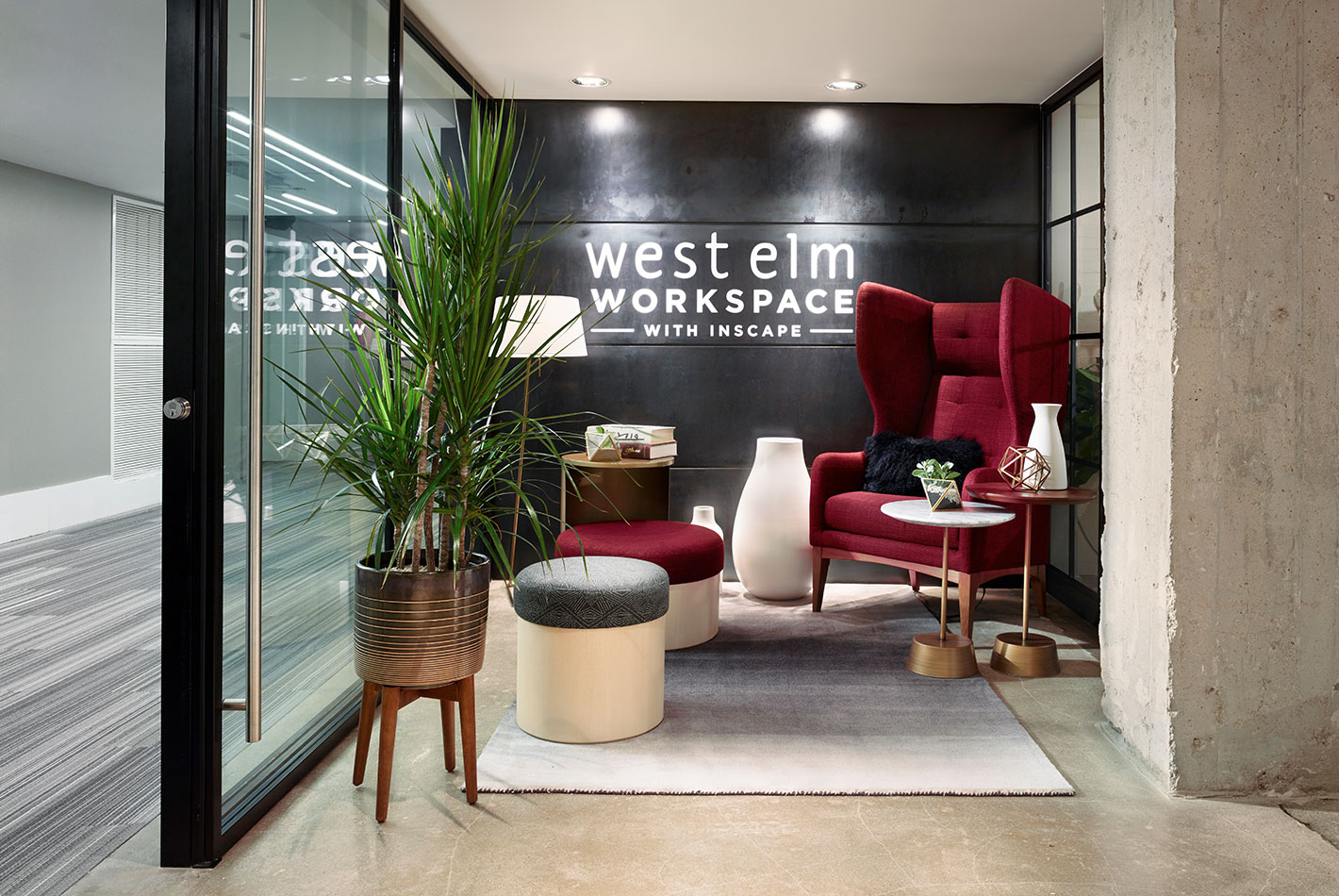 A full cranberry-colored wingback chair and several stools create a sales vignette at the West Elm NeoCon showroom