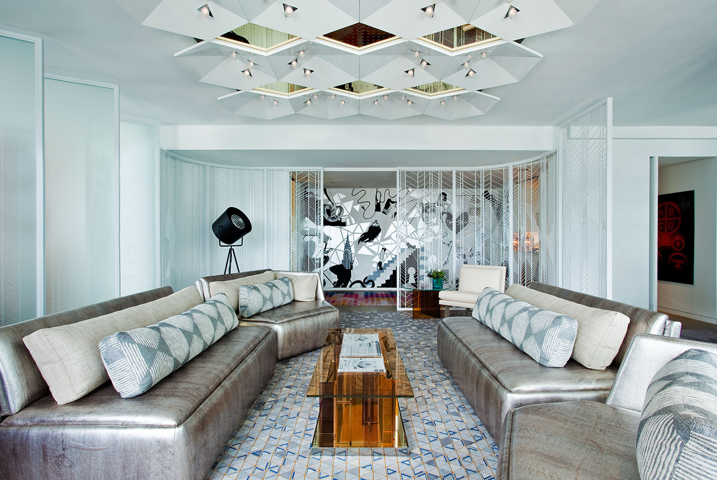 Multiple silver leather banquettes offer seating in the living room of the W Hotel Presidential Suite. A diamond patterned light fixture hangs above.