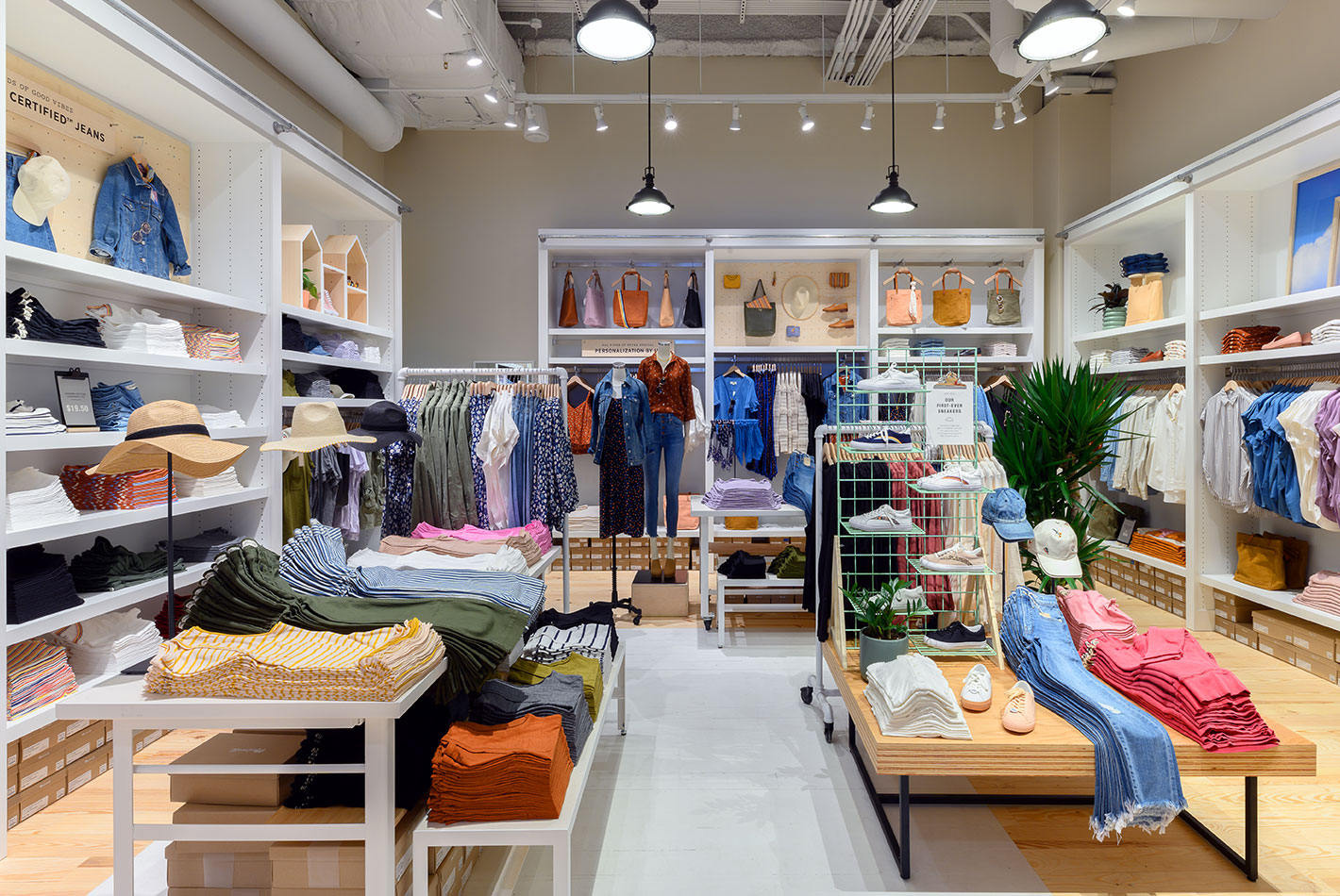 The women's department at Madewell features a collection of indigo-hued clothing and accessories. Dressing rooms nearby are covered in canvas panels.