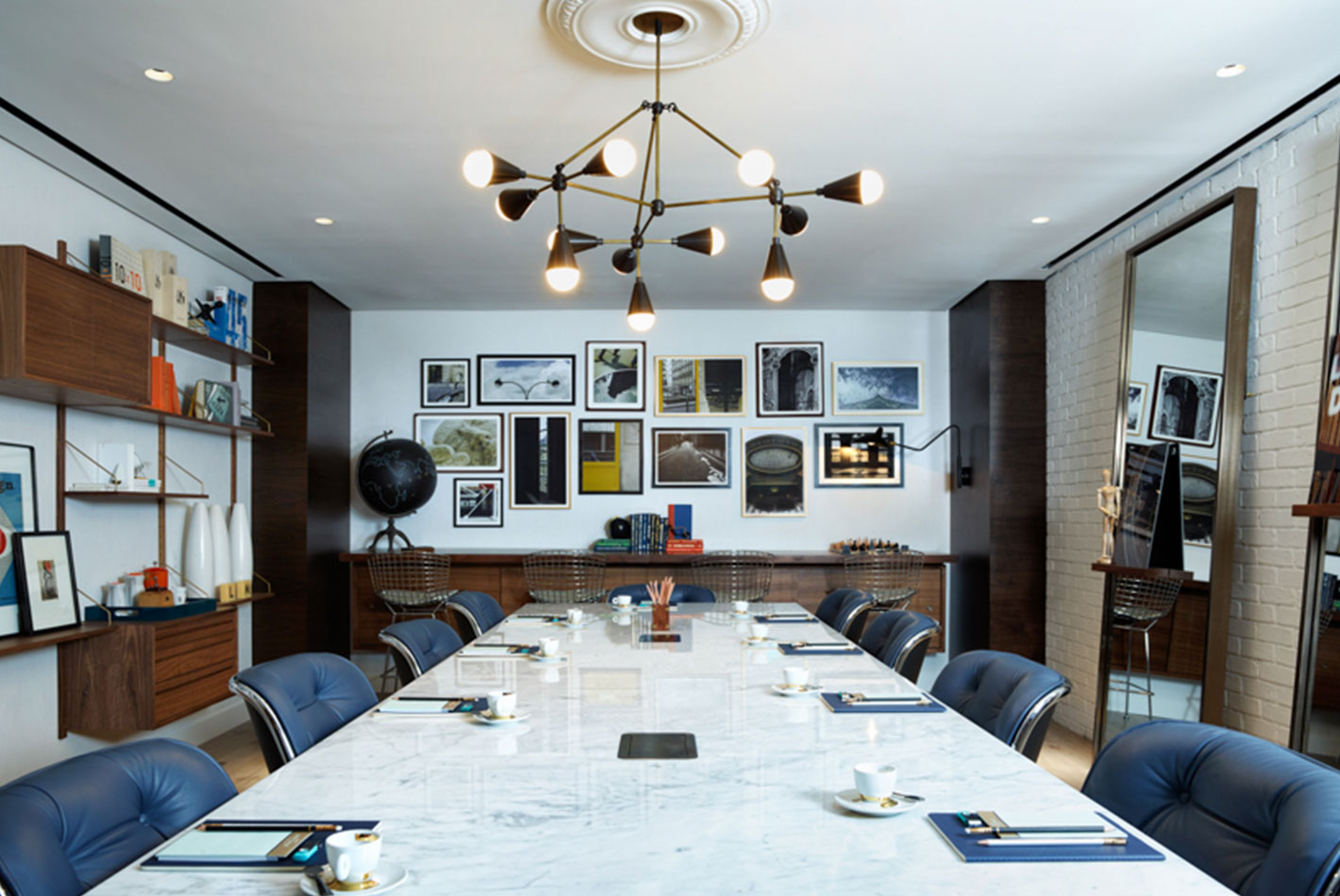 A full conference room at the Starwood Design Studio features a long white marble table and leather upholstered chairs.
