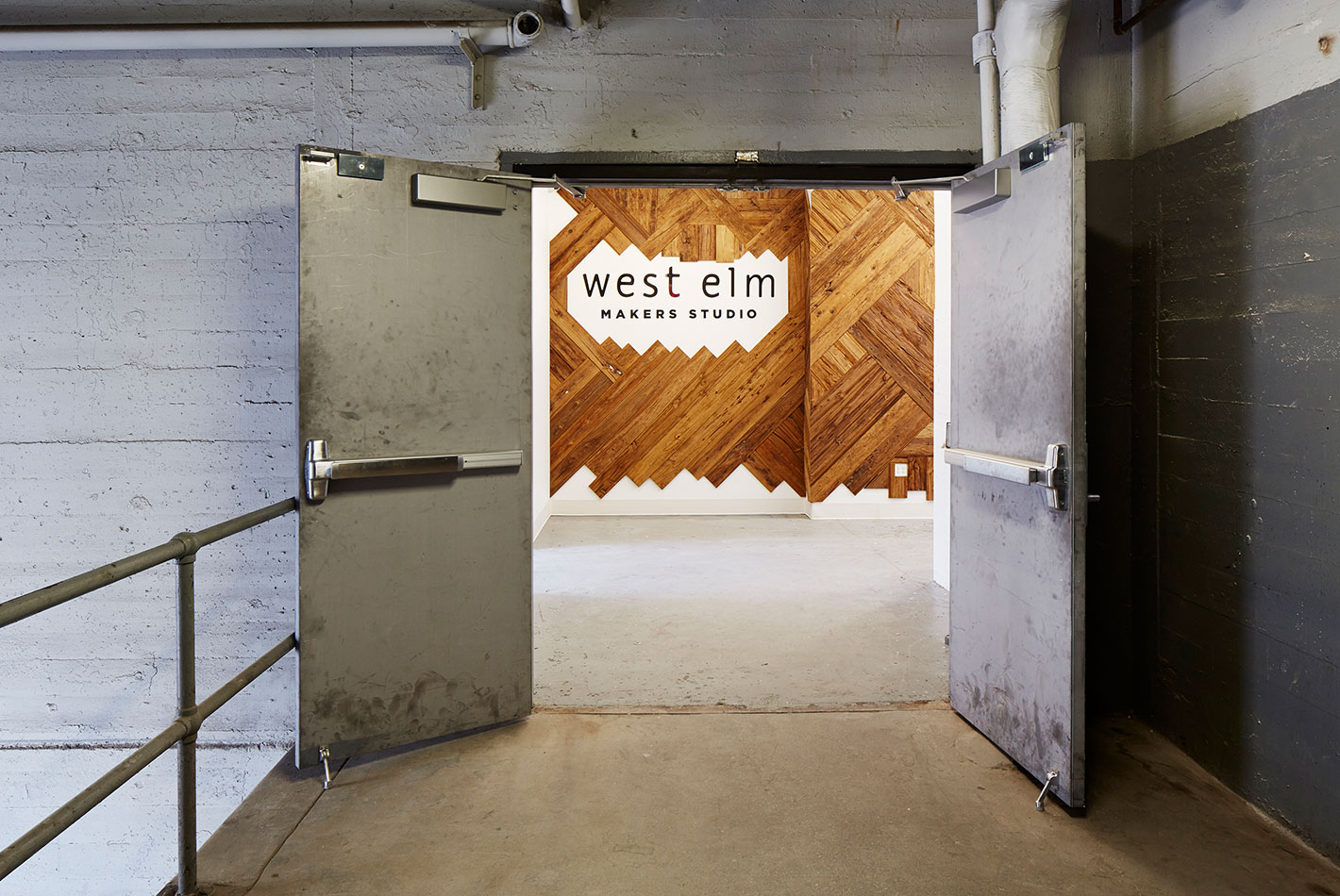 West Elm's logo rendered on a white wall with signature wood paneling at West Elm's Maker's Studio