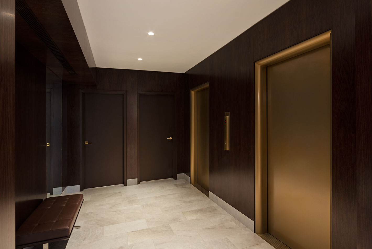 Walnut paneling lines the elevator bank at 1056 5th Avenue. Marble tile floors an satin brass elevator doors complete the space.