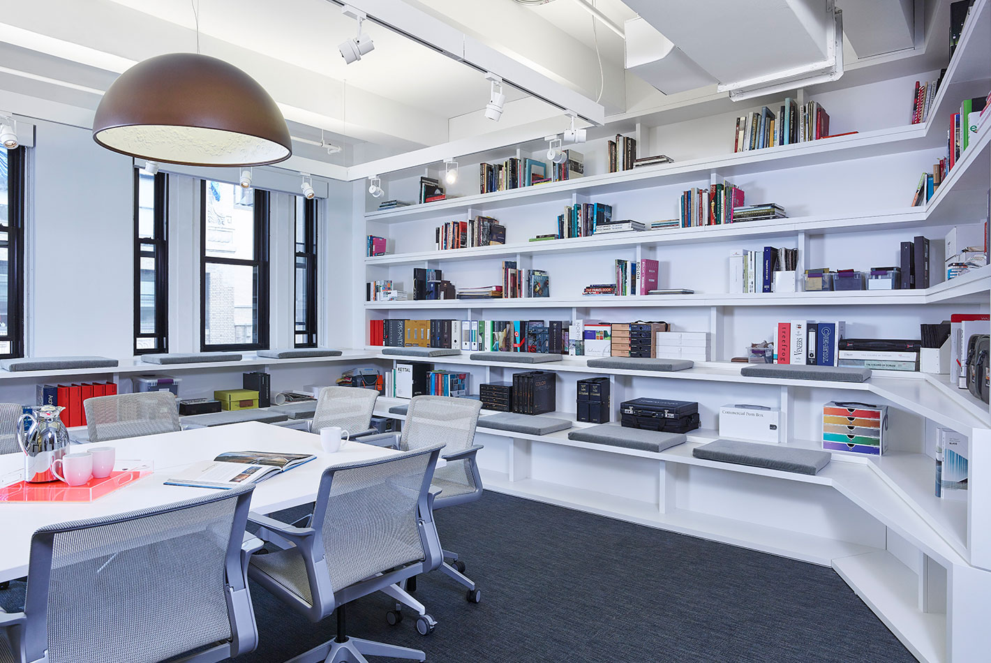 A pure white conference room with multiple shelving spaces and modern furniture at the Starwood Design Studio