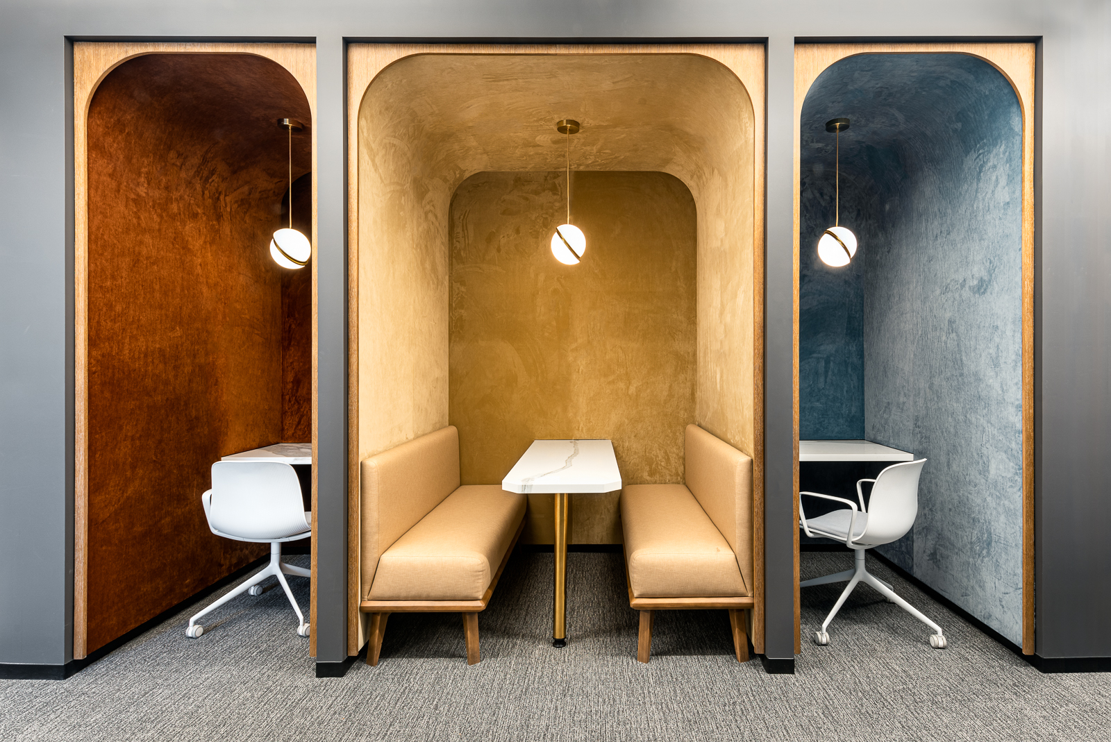 Three multicolored work cubbies with decorative lighting and velvet walls